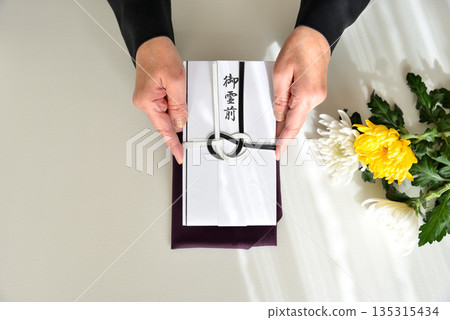 Image of handing over a condolence envelope 135315434