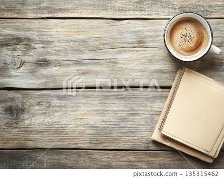 Top View of Freshly Brewed Coffee in a White Mug Resting Beside Stacked Kraft Paper Notebooks on a Rustic Wooden Surface 135315462