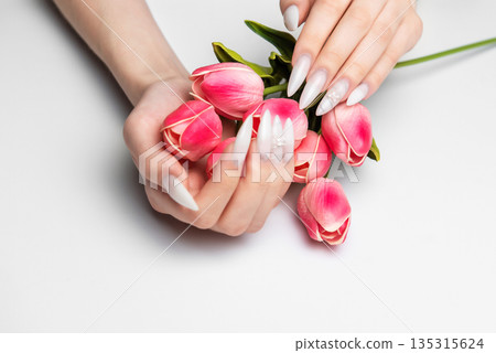 Woman's hands with long white nails holding tulips 135315624