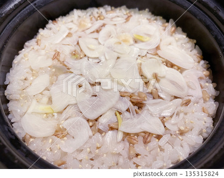 Freshly cooked brown rice in a clay pot with sliced garlic 135315824