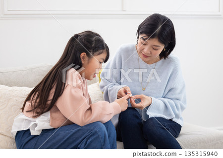 A mother putting a bandage on her elementary school daughter's finger A mother putting a bandage on her elementary school daughter's finger 135315940