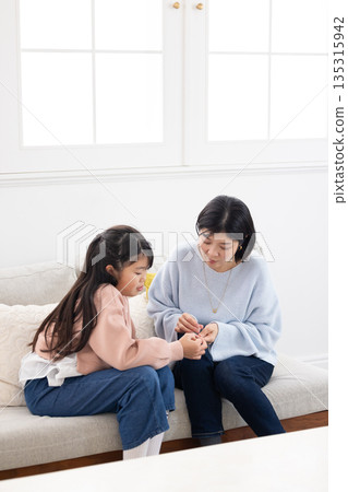 一位母親正在為一位上小學的女兒包紮手指。 一位母親正在為一位上小學的女兒包紮手指。 135315942