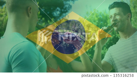 Toasting group of friends raising brown glass beer bottles in park under sunny Brazilian flag Toasting group of friends raising brown glass beer bottles in park under sunny Brazilian flag 135316258