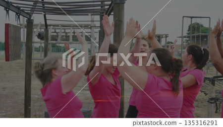 Celebrating women wearing pink shirts gathering at park obstacle course, with monkey bars 135316291