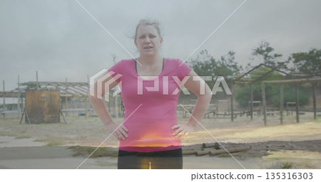 Training woman wearing pink shirt and tights navigating sandy obstacle course with metal drum Training woman wearing pink shirt and tights navigating sandy obstacle course with metal drum 135316303