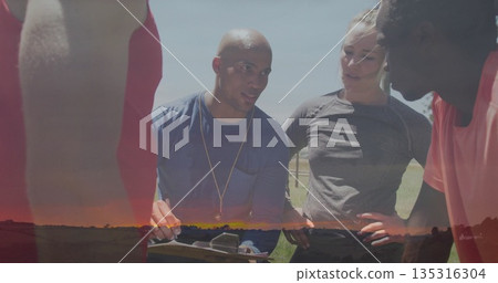 Explaining play strategy by Hispanic coach in gear holding clipboard on grass field, team coaching Explaining play strategy by Hispanic coach in gear holding clipboard on grass field, team coaching 135316304