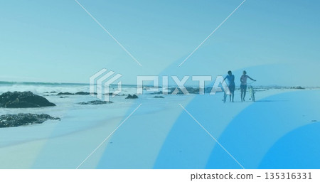 Walking couple in sportswear pushing bicycles along beach with rocks and lapping waves, copy space Walking couple in sportswear pushing bicycles along beach with rocks and lapping waves, copy space 135316331
