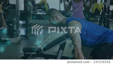 Man in sportswear pressing dumbbells on adjustable incline bench at gym, with free weights 135316358