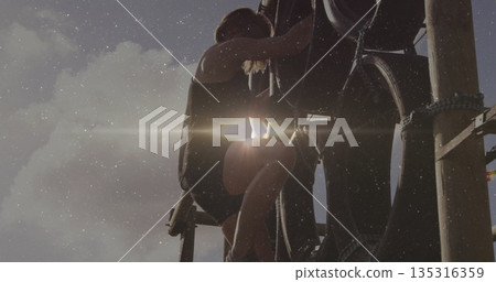 Climbing woman gripping stacked tires and wooden poles on obstacle course, with sunlight flare Climbing woman gripping stacked tires and wooden poles on obstacle course, with sunlight flare 135316359