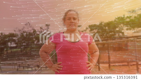 Posing woman showcasing pink shirt over black top on balcony with metal railing, with light trails 135316391