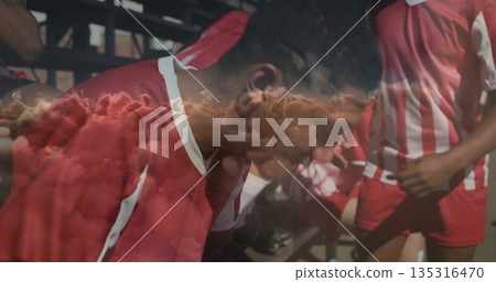 Sitting soccer player wearing red and white uniform hunching on sideline metal bench with bleachers Sitting soccer player wearing red and white uniform hunching on sideline metal bench with bleachers 135316470