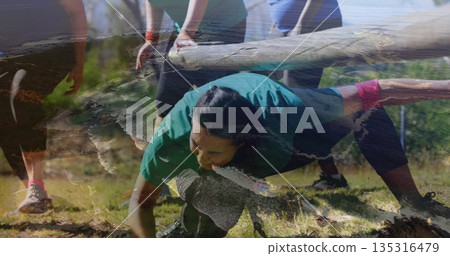 Crawling woman in teal athletic top maneuvering under wooden beam obstacle at park, with wristbands Crawling woman in teal athletic top maneuvering under wooden beam obstacle at park, with wristbands 135316479