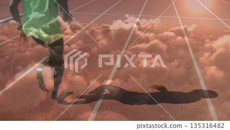 Sprinting athlete wearing green singlet and shorts on red track, with carbon fiber prosthetic blade 135316482