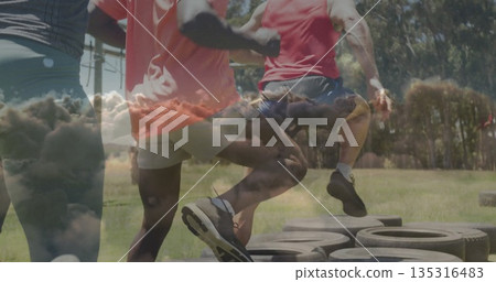 Stepping four athletes performing tire agility drill at grassy park field, with tractor tires Stepping four athletes performing tire agility drill at grassy park field, with tractor tires 135316483