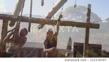 Climbing duo wearing sportswear navigating rope obstacles at outdoor course, with logs and beams Climbing duo wearing sportswear navigating rope obstacles at outdoor course, with logs and beams 135316507