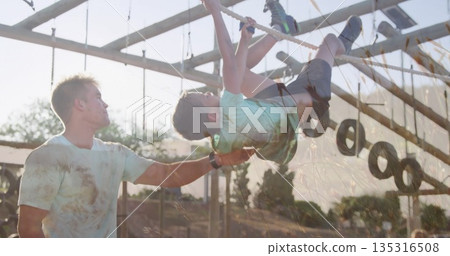 Climbing boy wearing mint green t-shirt gripping thick rope at outdoor wooden beam rig with tires Climbing boy wearing mint green t-shirt gripping thick rope at outdoor wooden beam rig with tires 135316508