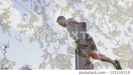 Performing dips man wearing sportswear on parallel bars at outdoor park with tree branches, leaves Performing dips man wearing sportswear on parallel bars at outdoor park with tree branches, leaves 135316519