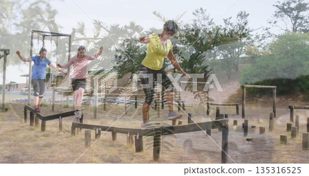 Balancing four women traversing wooden balance beams at outdoor obstacle course, with pull-up bars 135316525