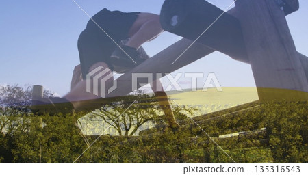 Climbing shirtless enthusiast gripping wooden beam obstacle in wildflower meadow, yellow blooms 135316543