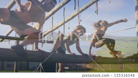 Climbing training partners navigating wooden obstacle course in grassy fenced field, ropes, beams Climbing training partners navigating wooden obstacle course in grassy fenced field, ropes, beams 135316548