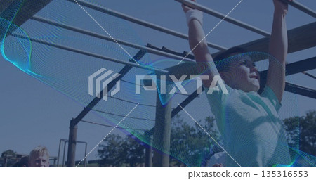 Swinging boy wearing light-green t-shirt and gloves climbing metal monkey bars at park, copy space Swinging boy wearing light-green t-shirt and gloves climbing metal monkey bars at park, copy space 135316553