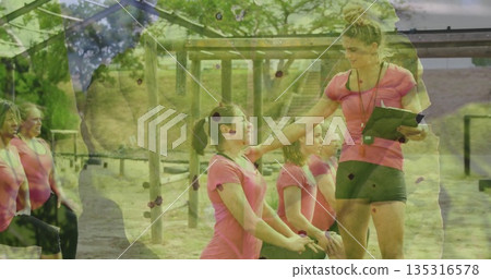 Leading coach guiding group lunging by wooden frame on grass, with clipboard, stopwatch, copy space 135316578