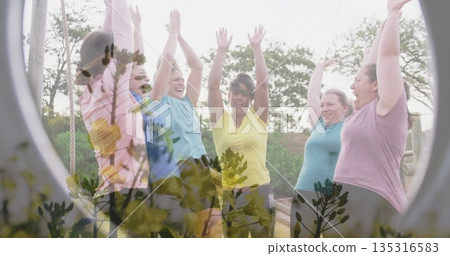 Cheering six women in activewear raising arms on wooden obstacle platform, with ropes and trees Cheering six women in activewear raising arms on wooden obstacle platform, with ropes and trees 135316583