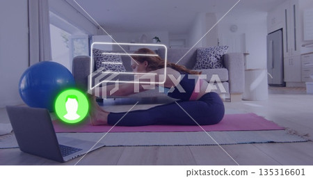 Stretching woman in sportswear reaching toes on yoga mat in living room, with laptop, exercise ball 135316601