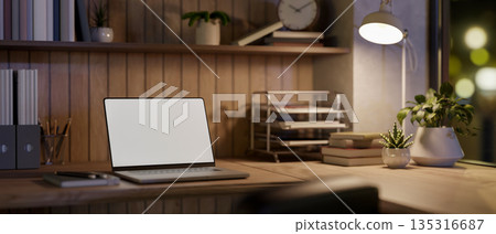 Blank screen laptop and book under lamp light on wooden table in dim room or office, Work or Study. Blank screen laptop and book under lamp light on wooden table in dim room or office, Work or Study. 135316687