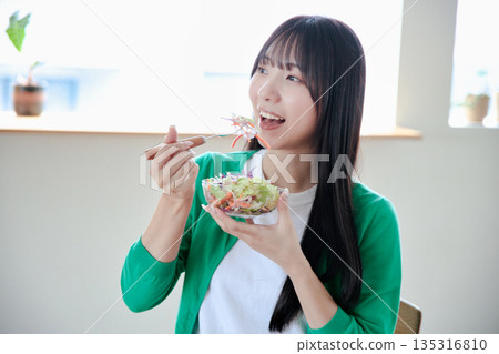 A young woman eating a salad A young woman eating a salad 135316810