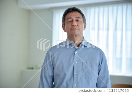 A smiling man in his 60s standing and looking at the camera 135317053