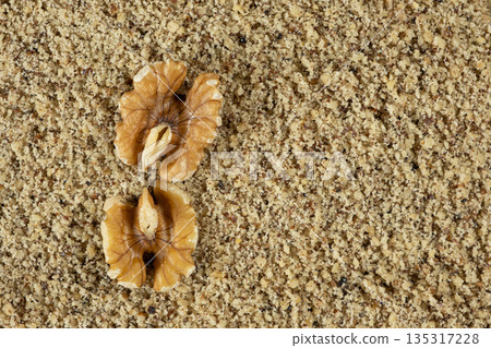 Two walnut halves on ground walnut kernels background top view place for text Two walnut halves on ground walnut kernels background top view place for text 135317228