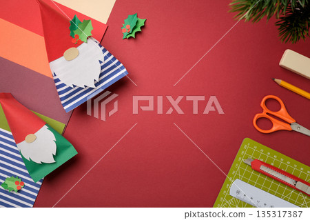 Handmade background with paper gnomes and art supplies on red background. Copyspace Handmade background with paper gnomes and art supplies on red background. Copyspace 135317387