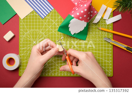 Making a craft. Hands cut out an oval nose from beige paper. Creative process. Making a craft. Hands cut out an oval nose from beige paper. Creative process. 135317392