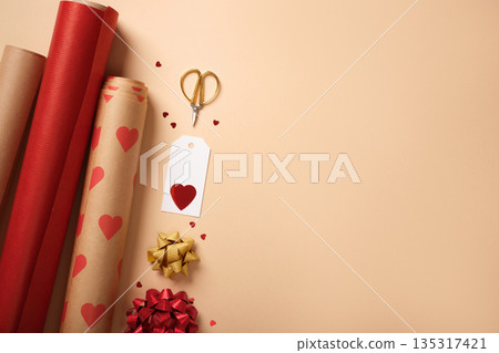 Gift wrapping background with red paper rolls, ribbon, scissors, tag and hearts. Copyspace. Gift wrapping background with red paper rolls, ribbon, scissors, tag and hearts. Copyspace. 135317421