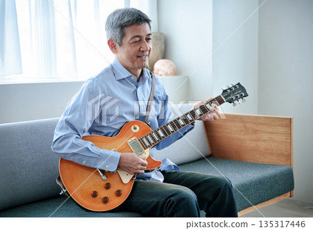 一位微笑的老人抱著一把電吉他 135317446