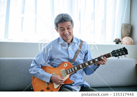 Smiling senior man holding an electric guitar Smiling senior man holding an electric guitar 135317448