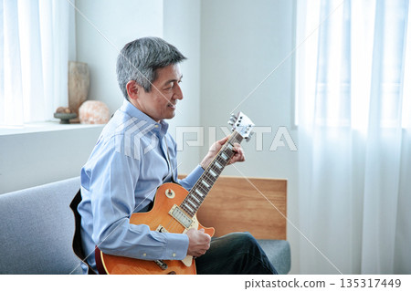 Smiling senior man holding an electric guitar Smiling senior man holding an electric guitar 135317449