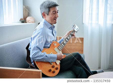 Smiling senior man holding an electric guitar Smiling senior man holding an electric guitar 135317450