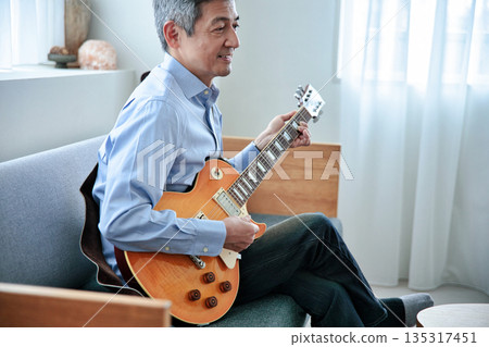 一位微笑的老人抱著一把電吉他 一位微笑的老人抱著一把電吉他 135317451