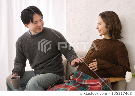 A young couple relaxing on the sofa, pregnant woman 135317468