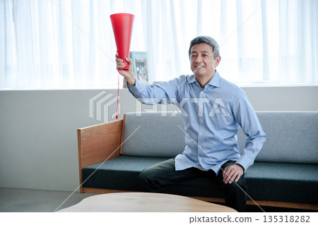 一位老年男子一邊看電視一邊歡呼 135318282