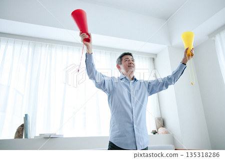 一位老年男子一邊看電視一邊歡呼 135318286