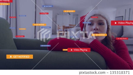 Leaning woman wearing Santa hat red sweater on green couch at home, with notifications, copy space Leaning woman wearing Santa hat red sweater on green couch at home, with notifications, copy space 135318371