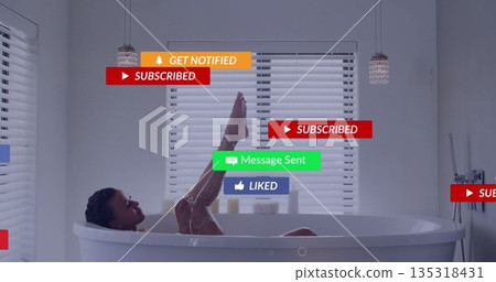 Leaning mid adult woman with braided hair bathing in bathtub, featuring soap lather notifications 135318431