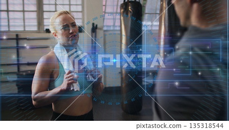 Catching breath woman wearing sportswear with towel in gym near punching bag with HUD, copy space Catching breath woman wearing sportswear with towel in gym near punching bag with HUD, copy space 135318544