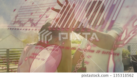 High-fiving senior woman and mature man sharing rooftop metal railing, with analytics music overlay 135318562