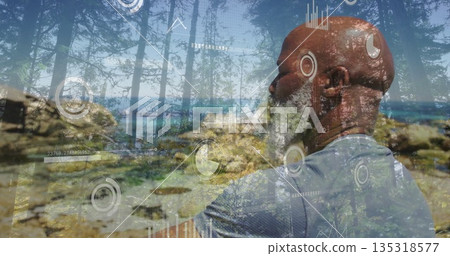 Standing man in gray athletic shirt viewing charts and graphs overlaying coastal forest, copy space 135318577