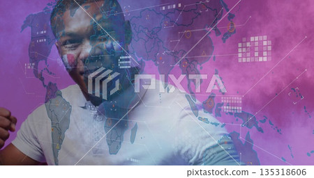Man wearing polo shirt interacting with hologram world map in studio with purple smoke, with icons 135318606