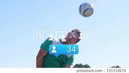 Soccer player wearing jersey jumping and heading ball on field, with overlay icons and bubble 135318678